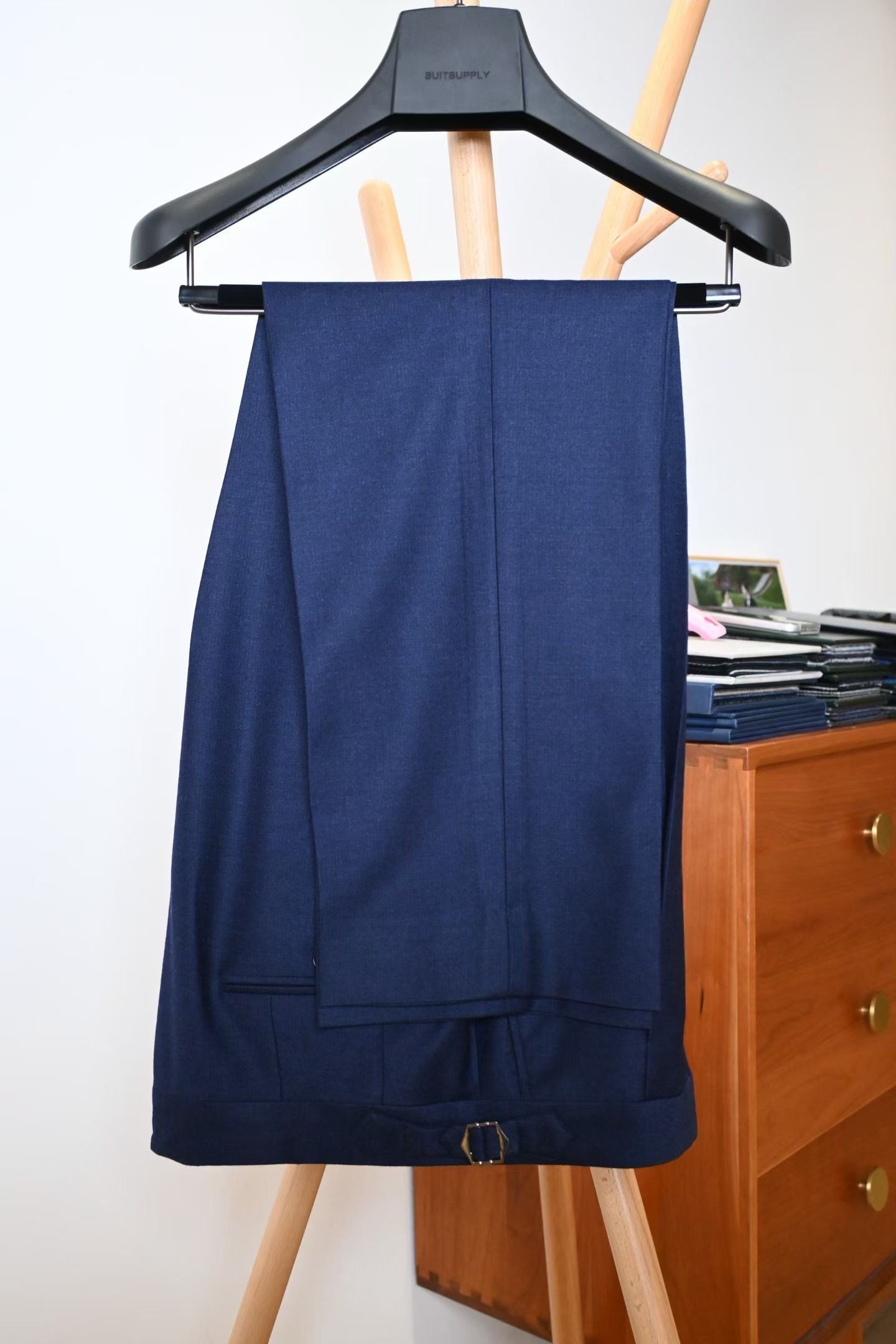 Blanc Sartorial 深藍西褲掛放，展示褲線及腰頭側扣